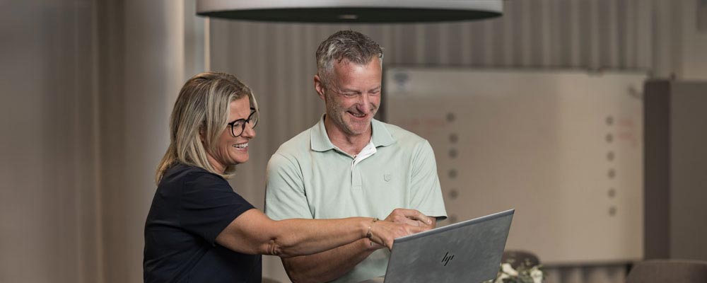 Två kollegor tittar på en dator och skrattar