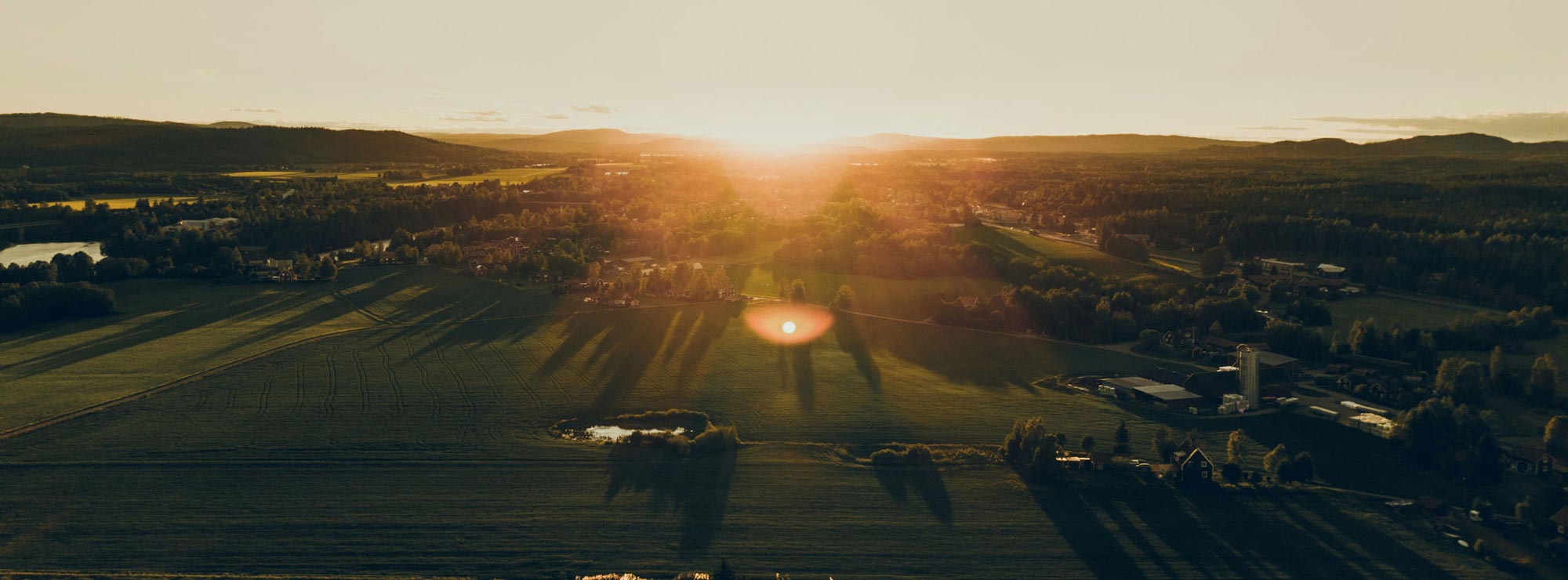 Solnedgång över landskap med ängar och skog